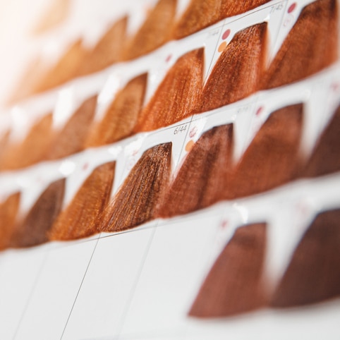 Nuancier de mèches de cheveux pour coloration capillaire aux teintes cuivrées et marron avec codes de couleurs.